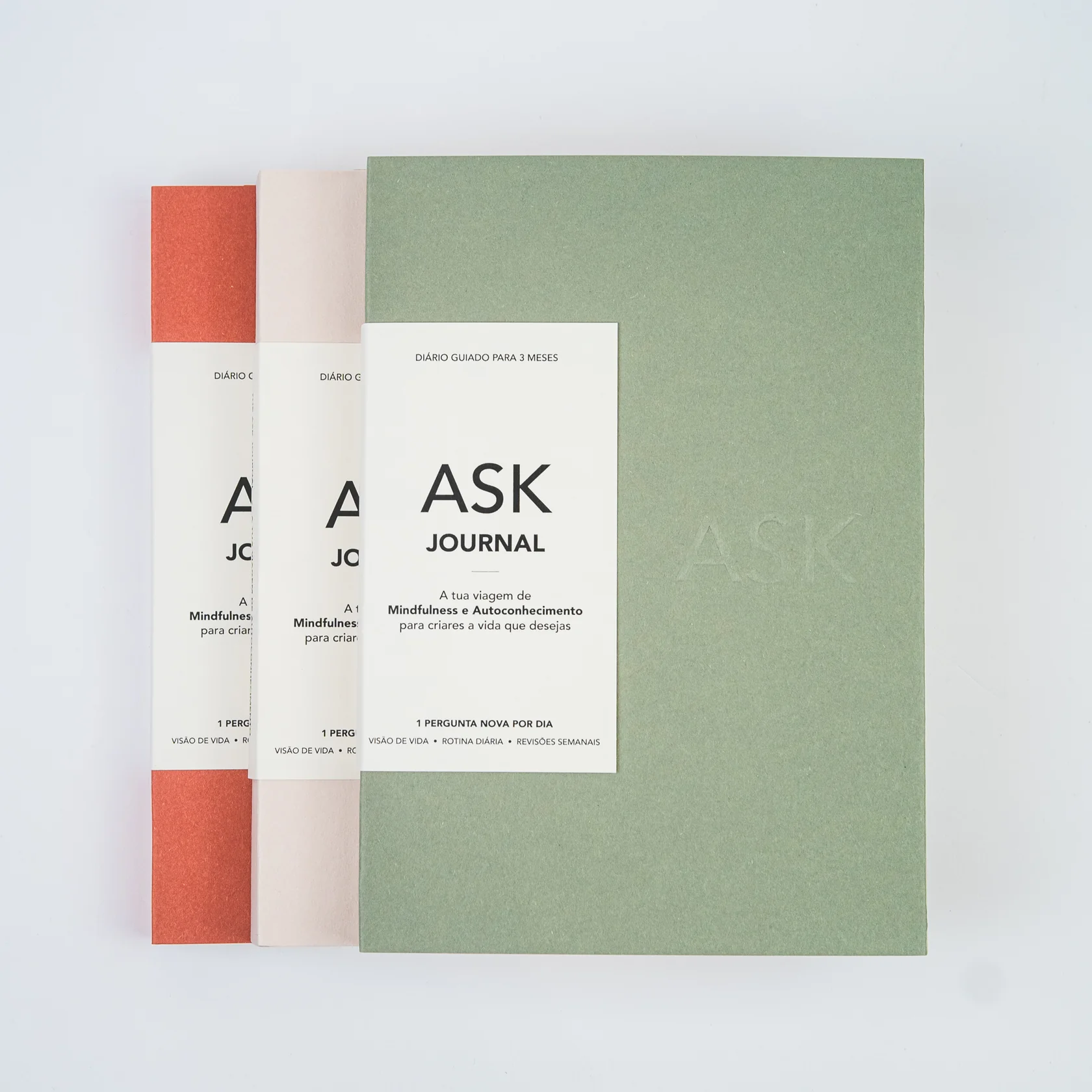 CADERNO DIÁRIO "THE ASK JOURNAL - PORTUGUÊS" ASK Três cadernos ASK Journal nas cores verde, branco e laranja dispostos lado a lado