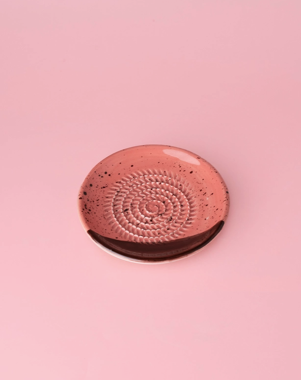 PRATO RALADOR PEQUENO "CHOCOLATE" ALFAR TIERRA COCIDA Prato cerâmico rosa com padrão espiral e faixa marrom sobre fundo rosa.
