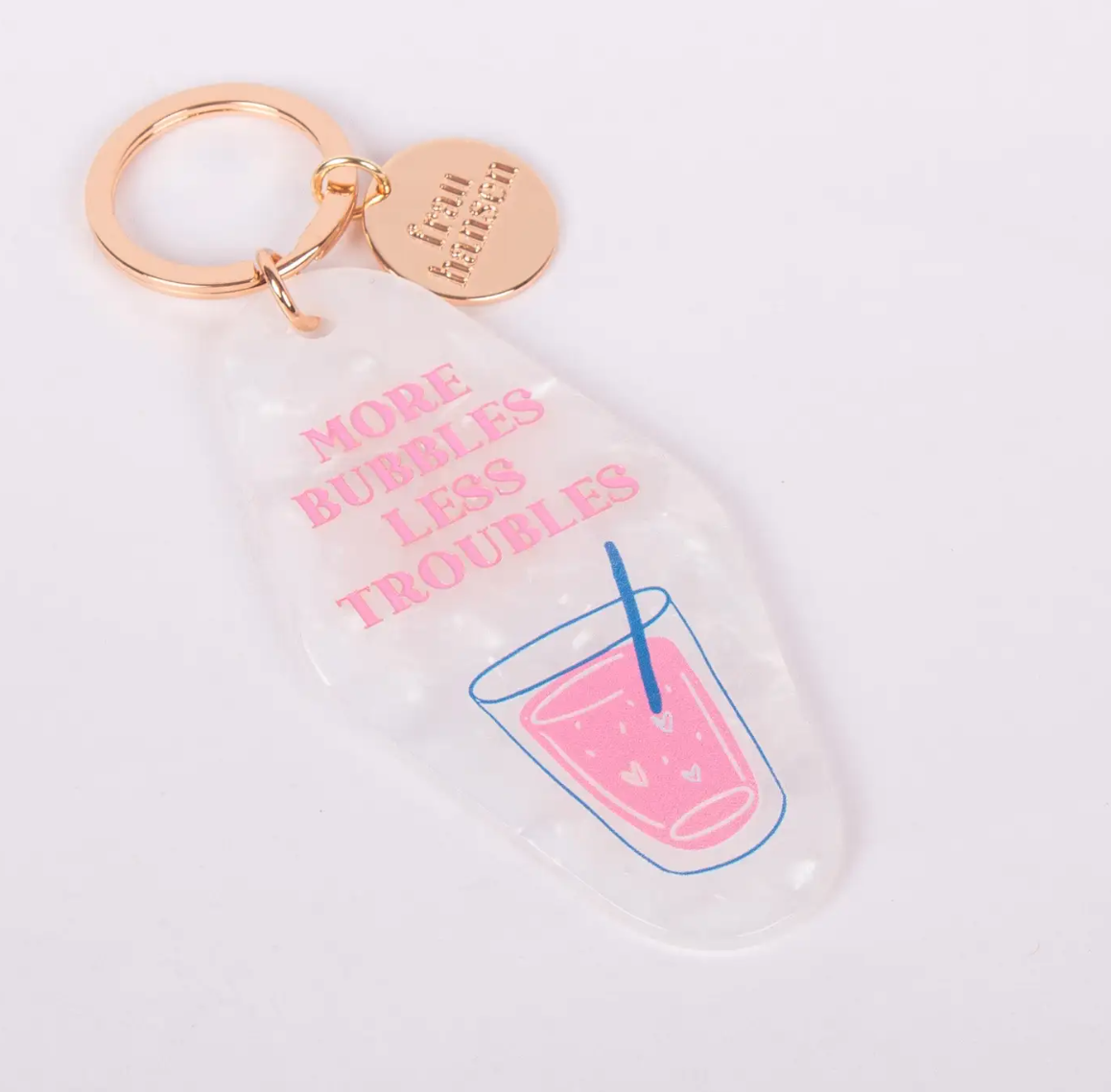 PORTA-CHAVES "MORE BUBBLES" - FRAU HANSEN Chaveiro transparente com anel dourado, texto rosa e ilustração colorida