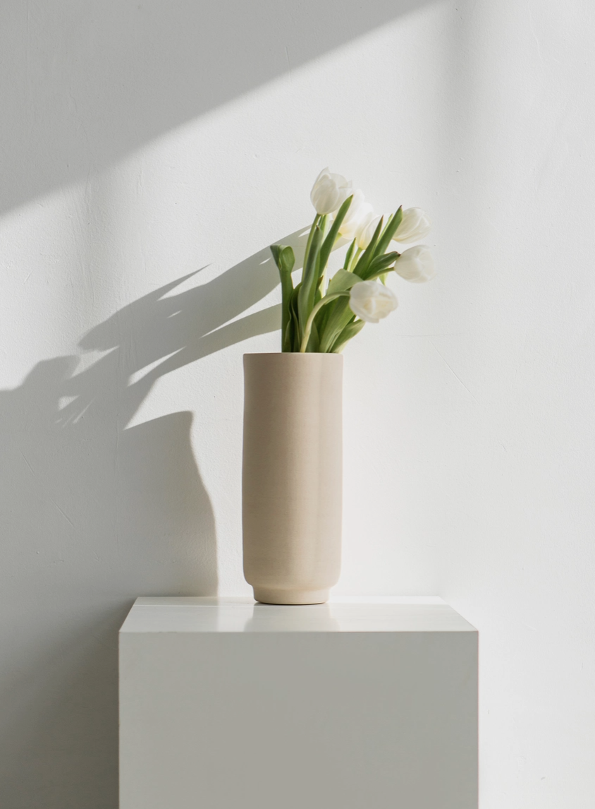 Sleek Vase - CACTUU Vaso de cerâmica bege com tulipas brancas num ambiente minimalista