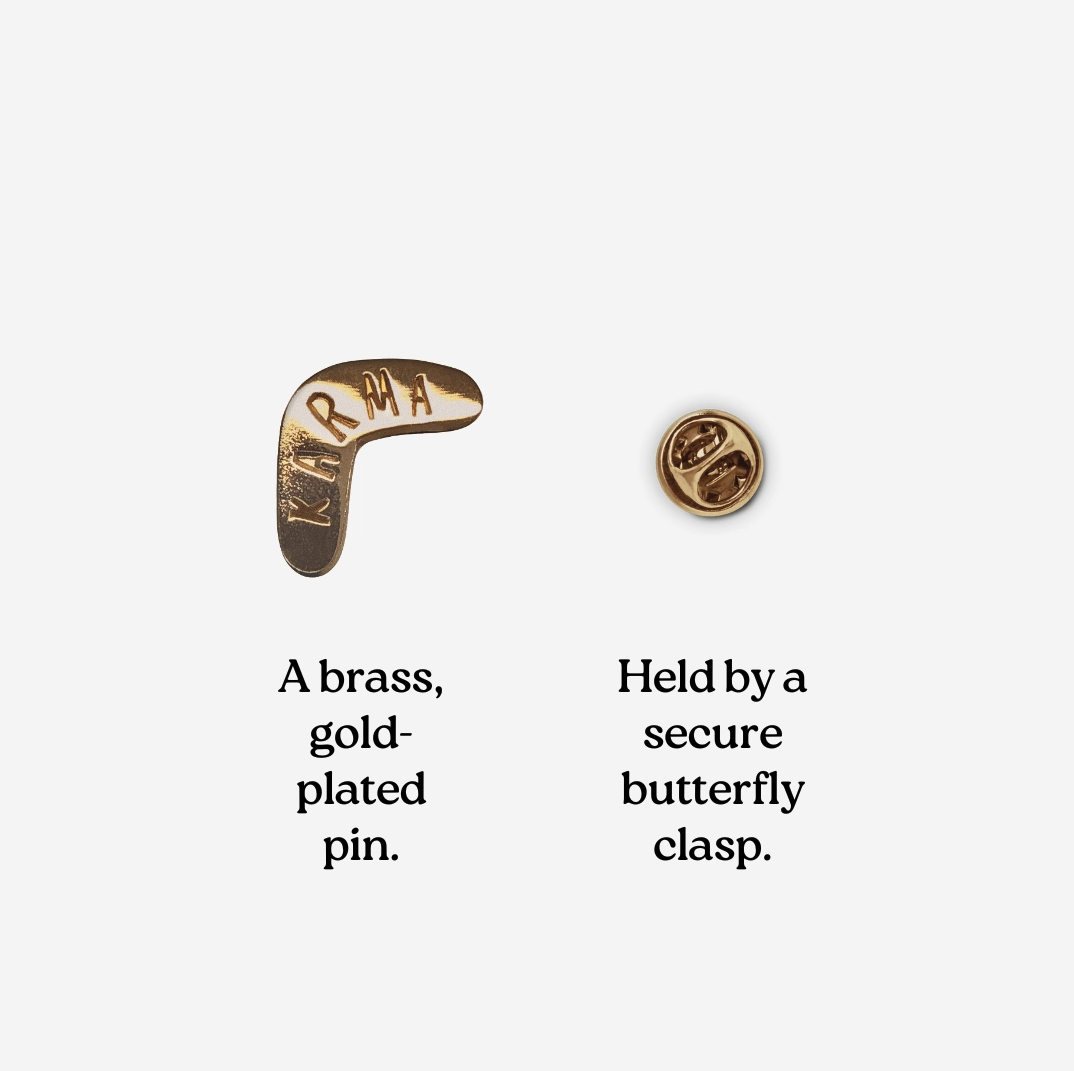 PIN "KARMA" TYPEALIVE Alfinete dourado em forma de bumerangue com a palavra KARMA