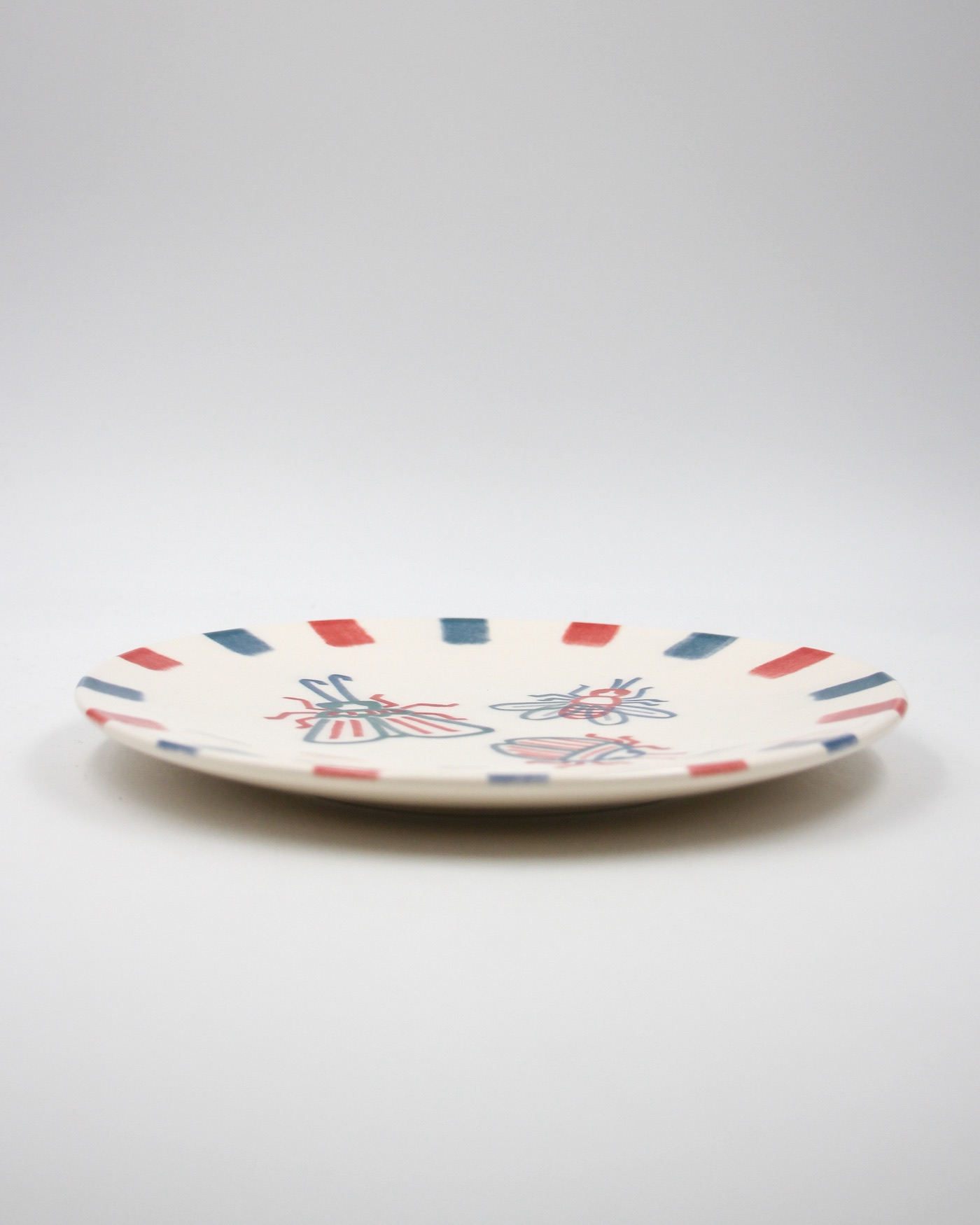 PRATO ILUSTRADO "BICHOS" DIOGO PAIXÃO E PÓ DE BARRO Prato cerâmico decorado com riscas coloridas e insetos.