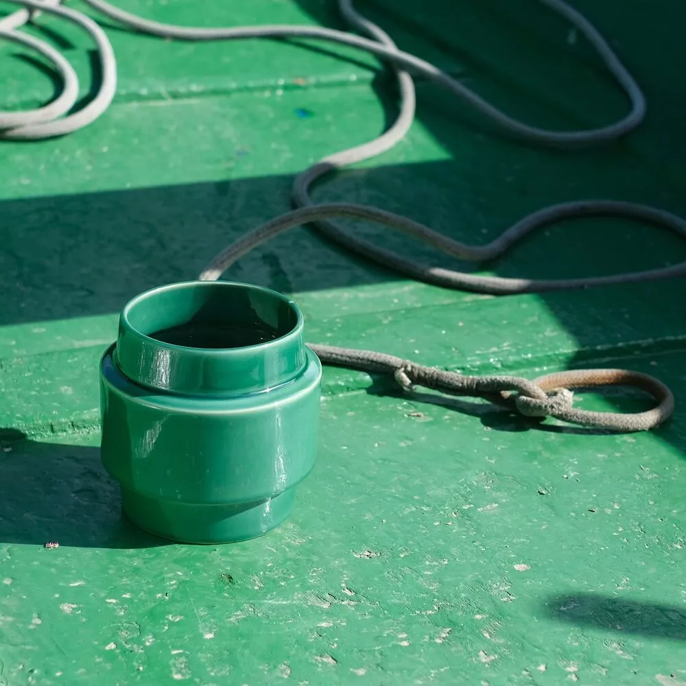 VASO "RECORTE FAIXA" VERDE ÁGUA CASA ATLÂNTICA Vaso verde de cerâmica com corda ao lado em superfície verde