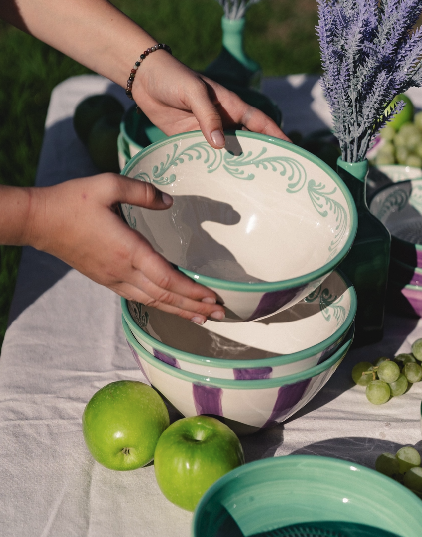 TIGELA DE SERVIR "VIOLETA" ALFAR TIERRA COCIDA Conjunto de taças e pratos cerâmicos verdes e roxos com decoração em ambiente de picnic.