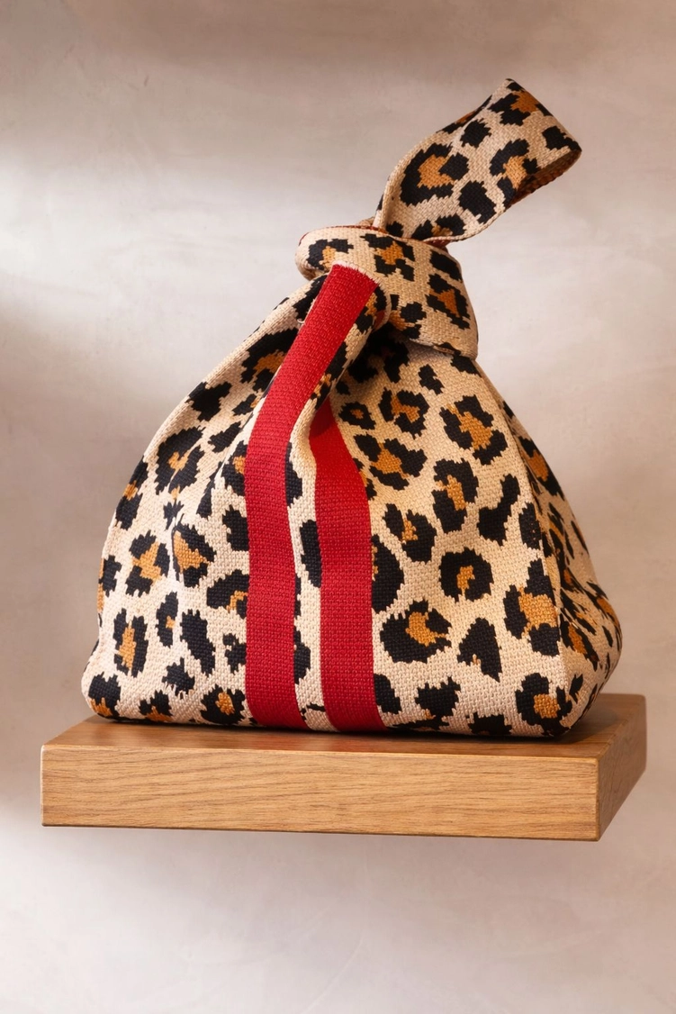 MALA DE MALHA LEOPARDO M- TOKEII KNIT STUDIO Mala tecido animal print castanho preto bege com faixa vermelha sobre superfície de madeira
