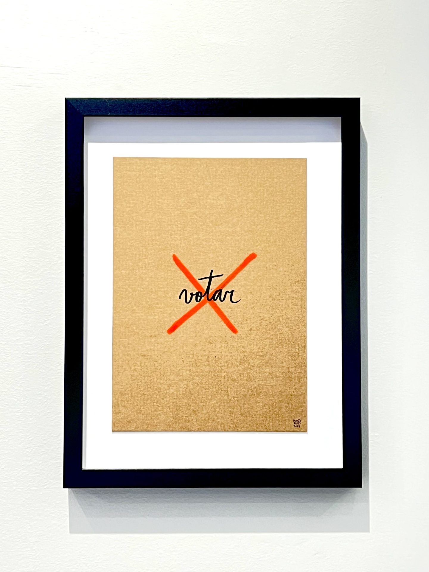 ORIGINAL "VOTAR" MARTA NUNES Quadro com moldura preta com impressão de 'X' vermelho e palavra 'votar' numa parede branca