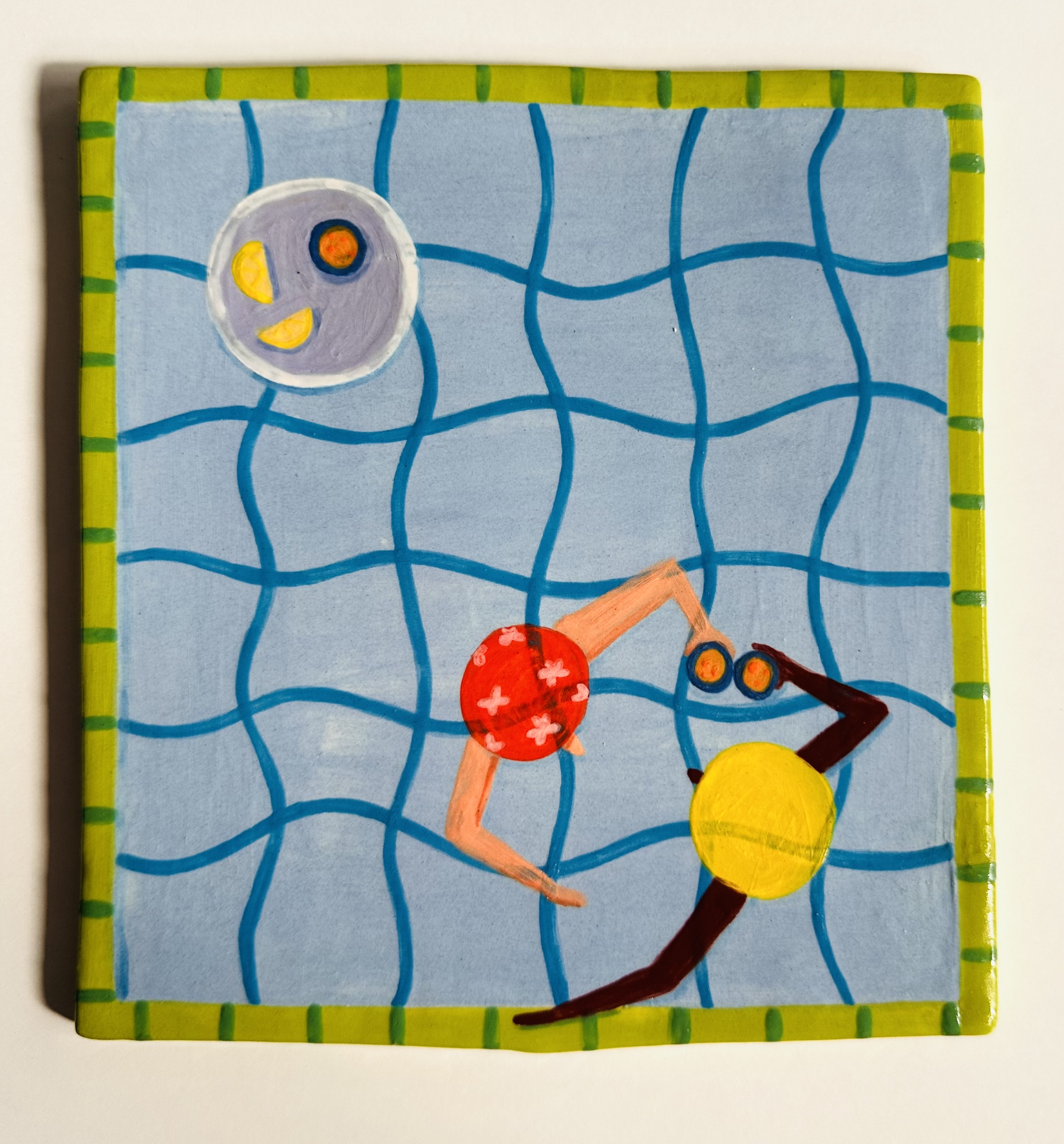 AZULEJO PISCINA COPOS KIKA 14X14CM Placa decorativa quadrada com ilustração de duas figuras numa piscina azul e borda verde com riscas