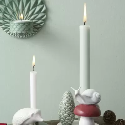 Conjunto de castiçais decorativos em cerâmica com velas acesas e decoração natural