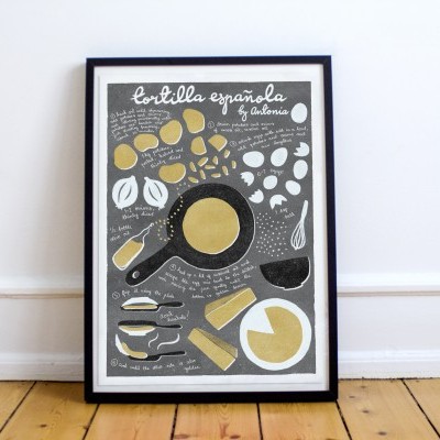 Póster emoldurado com ilustração e texto sobre tortilla española em cores branco, amarelo e preto