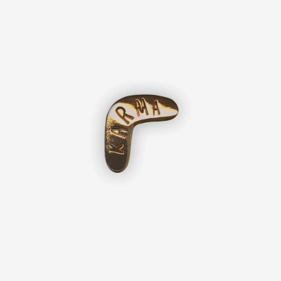 Botão dourado em forma de bumerangue com a palavra KARMA