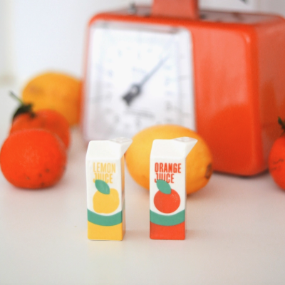 Embalagens pequenas de sumo de limão e laranja com frutas e medidor laranja ao fundo