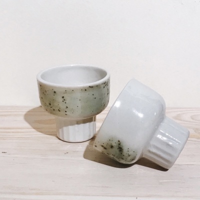Dois copos ou tigelas de cerâmica branca com base estriada e parte superior esverdeada manchada