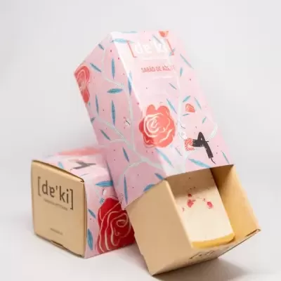 Sabonetes em barra com embalagem rosa estampada com flores e folhas, etiqueta com texto [de'ki] e SABÃO DE ROSE número 4
