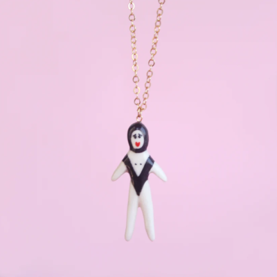 Colar com pendente figura humana cerâmica branca e preta, corrente dourada, fundo rosa