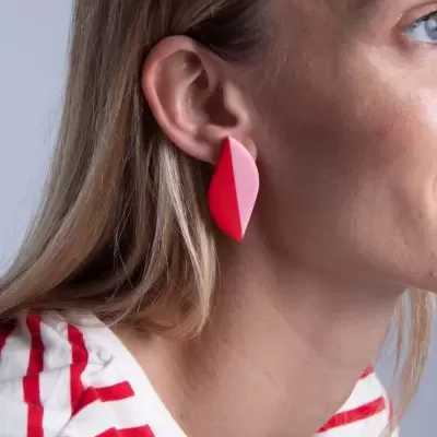 Brinco geométrico vermelho e rosa em orelha feminina