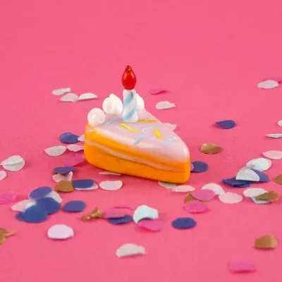 Miniatura decorativa de fatia de bolo com vela e confetti