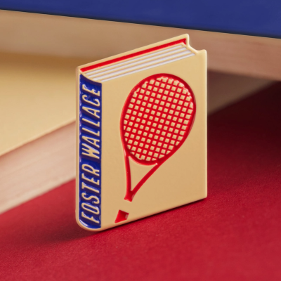 Pin em forma de livro com raquete de ténis e texto FOSTER WALLACE