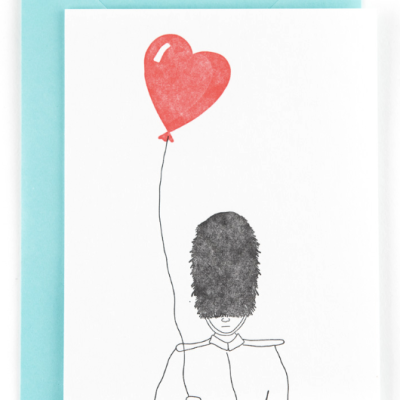 Cartão com desenho de guarda da rainha a segurar balão em forma de coração vermelho.