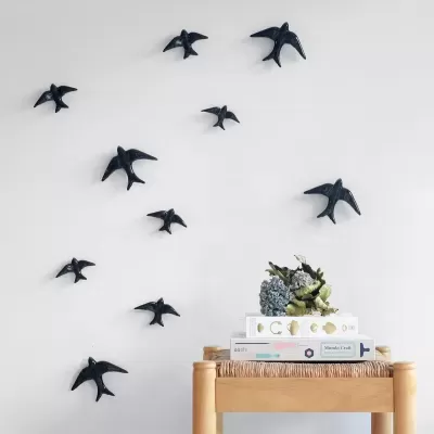 Decoração de pássaros pretos em parede branca e mesa com livros e arranjo floral
