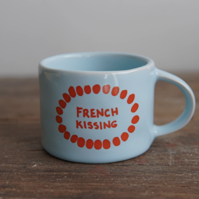 Caneca azul clara com texto vermelho 'FRENCH KISSING' e padrão de pontos vermelhos