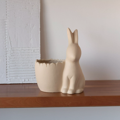 Vaso decorativo em cerâmica bege com design de coelho e recipiente ao lado