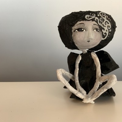 Escultura decorativa de mulher sentada em preto e branco