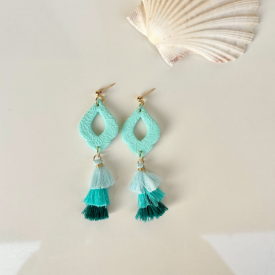 Brincos pendentes azul e verde com tassel e concha ao lado