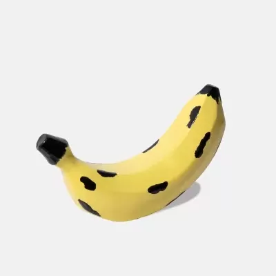 Objeto decorativo em forma de banana amarela com manchas pretas.