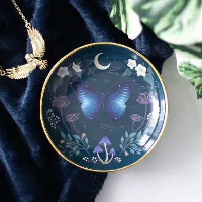 Prato decorativo azul com borboleta e motivos naturais com borda dourada.