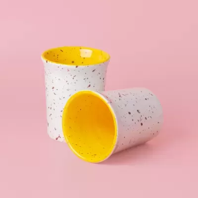 Dois copos cerâmicos branco com manchas coloridas e interior amarelo