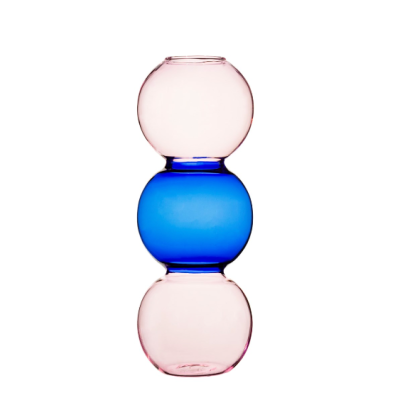 Vaso de vidro formado por três esferas, duas rosa translúcido e uma azul no meio.