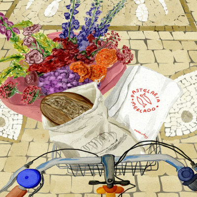 Cesto de bicicleta com flores e pão em sacos, chão com calçada portuguesa