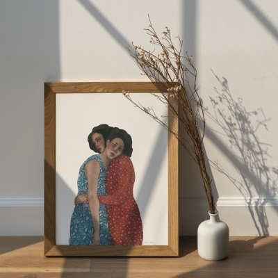 Quadro de ilustração de duas mulheres abraçadas com vestidos azul e vermelho, moldura de madeira, junto a vaso com ramos secos