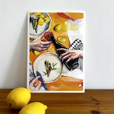 Postal com ilustração de mesa com pratos, mãos a servir vinho, limões e pano xadrez sobre mesa de madeira.