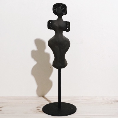 Escultura decorativa preta de figura feminina estilizada com base redonda preta sobre madeira clara