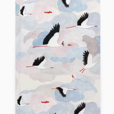 Caderno com ilustração de cegonhas a voar entre nuvens coloridas
