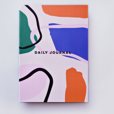 Caderno com capa colorida abstrata e texto DAILY JOURNAL