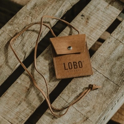 Carteira ou bolsa pequena castanha de couro com fecho e cordão sobre madeira