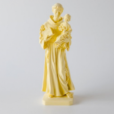 Estátua amarela de figura religiosa com criança e livro em fundo branco