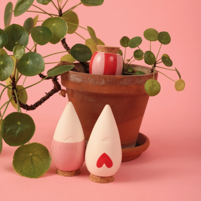 Vaso de barro com planta e três frascos cerâmicos com tampas de cortiça em fundo rosa