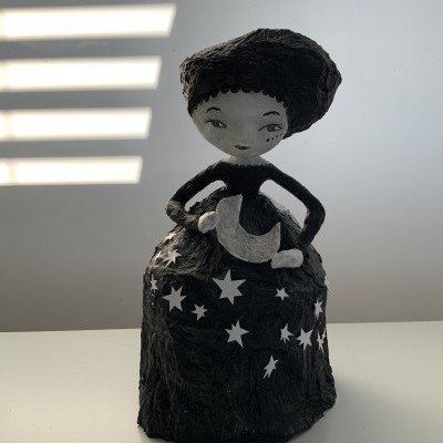 Escultura feminina preta e branca com vestido decorado com estrelas