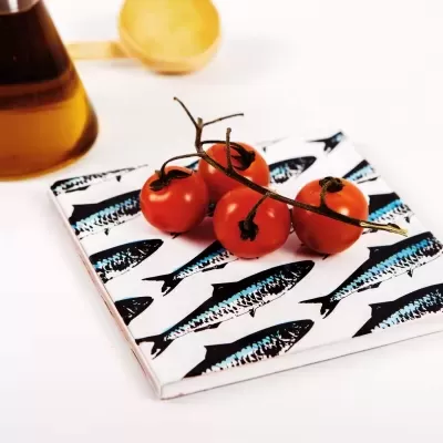 Tomates cereja sobre prato decorado com peixes, recipiente de vidro castanho ao fundo