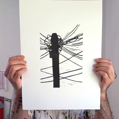 Impressão monocromática preta em papel branco segurado por duas mãos tatuadas