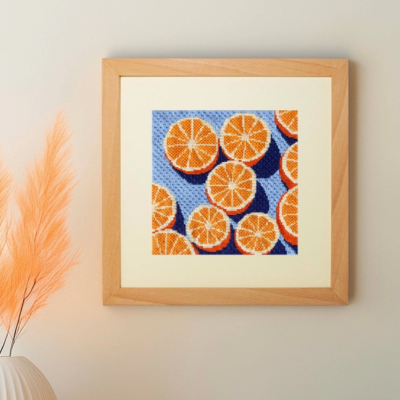 Quadro ponto cruz com fatias de laranja em fundo azul na parede