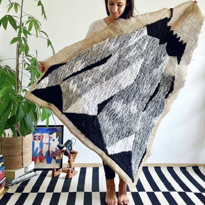 Tapete triangular cinza e preto com padrão geométrico segurado por mulher