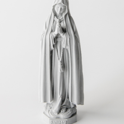 Estátua branca de Nossa Senhora de Fátima com manto e terço, base com texto FATIMA.