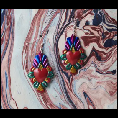 Brincos de coração vermelho com detalhes coloridos sobre superfície marmoreada