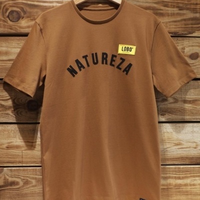 T-shirt castanha com texto NATUREZA e etiqueta LOBO pendurada em cabide de madeira