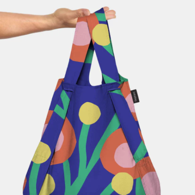 Saco de tecido com padrão colorido de flores, segurado por uma mão