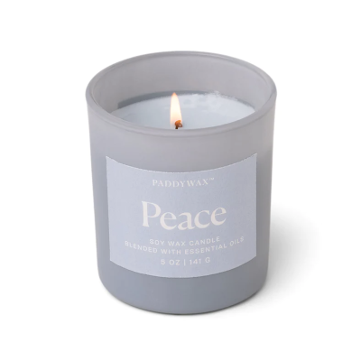 Vela em copo de vidro cinzento fosco com etiqueta azul clara e chama acesa